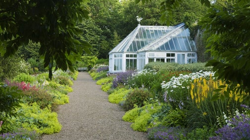 Conservatory and borders in the flower garden in July at Arlington Court, Devon